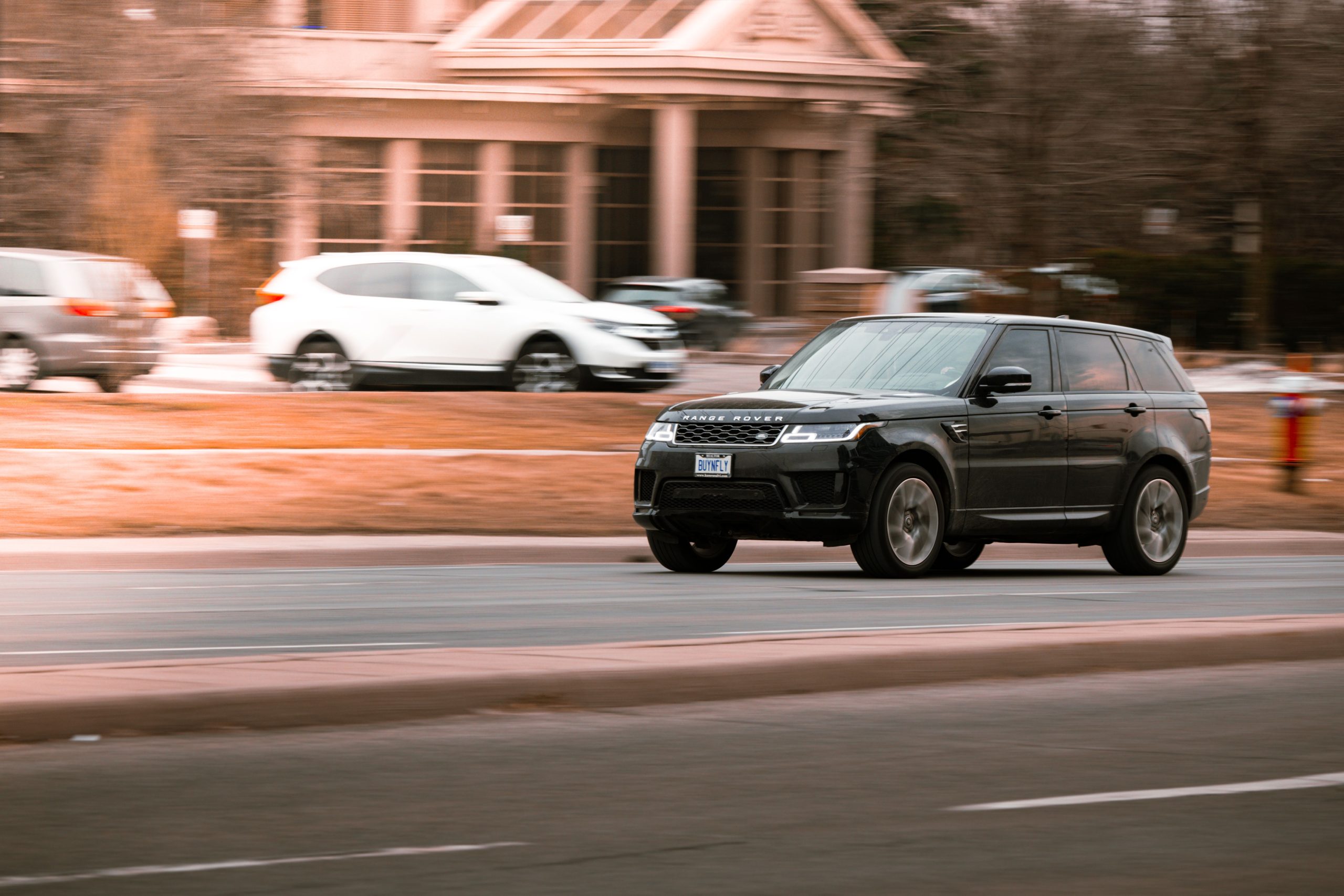A luxury Range Rover speeding on a city street in Canada, captured with motion blur highlighting its velocity.